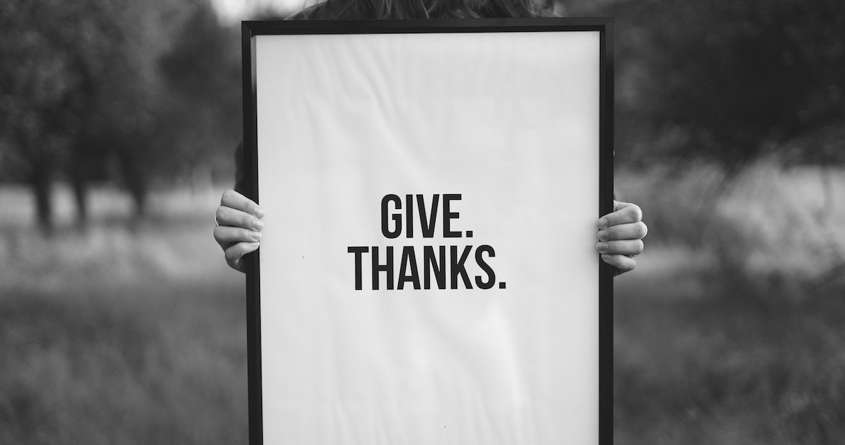 A person holding a give thanks sign